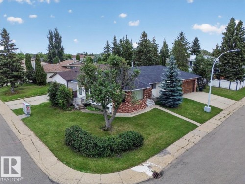 Single-story residence with a dark shingle roof, brick and siding exterior, and an attached garage with a wood-finish door - 2907 49 Street Nw, Edmonton, AB 