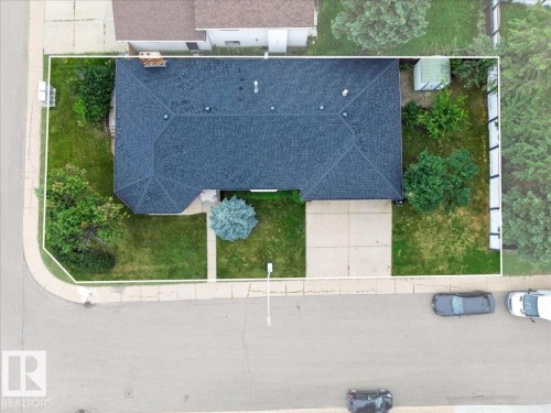 Expansive corner lot featuring a dark shingled roof, concrete driveway, front walkway, and mature trees - 2907 49 Street Nw, Edmonton, AB 