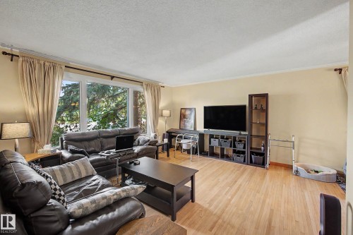Light-toned wood-finish flooring with a large picture window, crown molding, and neutral wall tones - 11431 51 Avenue Nw, Edmonton, AB 