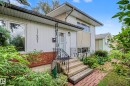 Front exterior featuring multi-level architecture, a brick accent wall, white siding, and an ornate wrought iron railing at the entrance - 11431 51 Avenue Nw, Edmonton, AB 