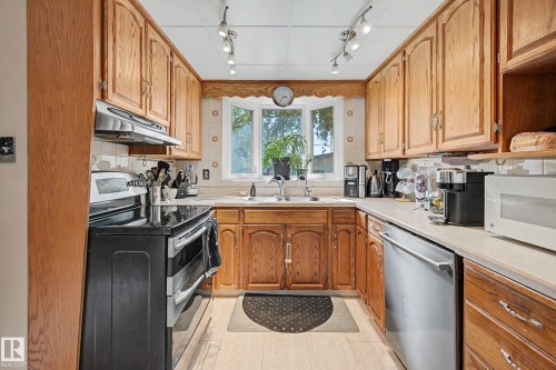 Hardwood cabinetry with stainless steel appliances, tile backsplash, laminate countertops, and track lighting - 11431 51 Avenue Nw, Edmonton, AB 