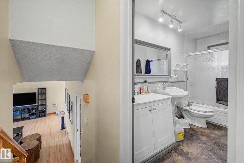 Full bathroom with a white vanity, pedestal sink, track lighting, and a shower-tub combination with a sliding glass door - 11431 51 Avenue Nw, Edmonton, AB 