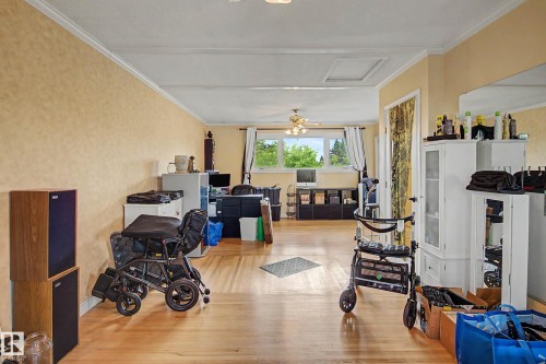 Expansive room featuring wood-finish flooring, crown molding, and multiple windows with exterior scenery - 11431 51 Avenue Nw, Edmonton, AB 