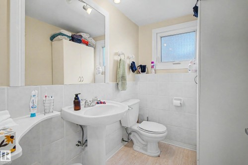 Pedestal sink with chrome faucet, toilet, wall-mounted mirror, and a window with privacy glass - 11431 51 Avenue Nw, Edmonton, AB 