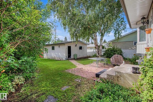 Expansive backyard with a manicured lawn, mature trees, and a brick paver patio - 11431 51 Avenue Nw, Edmonton, AB 
