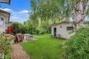 Expansive lawn with mature trees, a detached auxiliary structure, and a brick paver patio - 11431 51 Avenue Nw, Edmonton, AB 