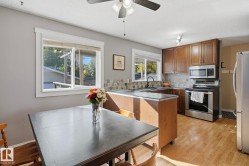 Kitchen featuring wood-finish flooring, wood cabinetry, stainless steel appliances, and a tiled backsplash - 