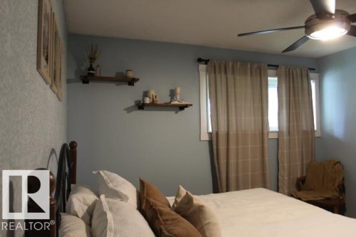 Ceiling fan with integrated lighting, wall-mounted shelving, and windows with white trim - 64 Apache Crescent, Leduc, AB 
