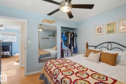 Room featuring a built-in closet with hanging rods, wood-finish flooring, and a ceiling fan with integrated lighting - 