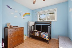 Wood-finish flooring with a ceiling fan and a window featuring a white frame - 