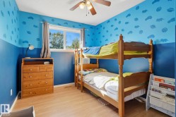 Light wood-finish flooring, a ceiling fan with integrated lighting, and a window with gray drapes - 