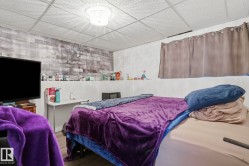 Textured accent wall, ceiling grid with recessed lighting, and wood-finish flooring - 
