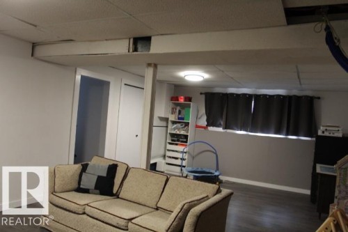 Recessed lighting, drop ceiling, wood-finish flooring, interior door, window with installed curtain rod - 64 Apache Crescent, Leduc, AB 