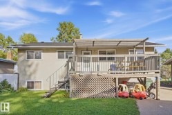 Exterior featuring a raised wooden deck with a slatted pergola, stucco siding, and a manicured lawn - 