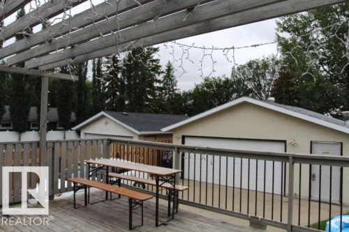 Wood-finish deck with slatted railing and overhead pergola structure - 64 Apache Crescent, Leduc, AB 