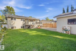 Expansive green lawn with a two-story residence featuring a ground-level patio and an elevated wood-finish deck - 
