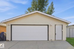 Detached garage with a paneled overhead door, separate access door, and stucco exterior finish - 