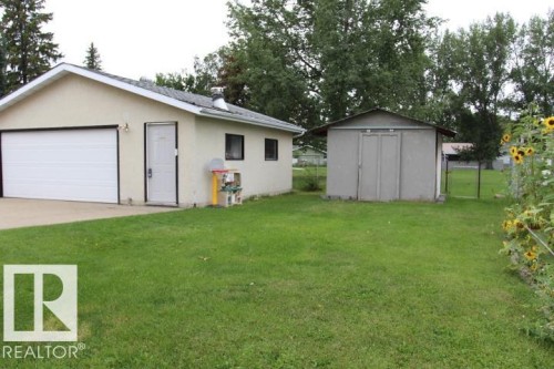 Attached garage with a white overhead door and an exterior entry door - 64 Apache Crescent, Leduc, AB 