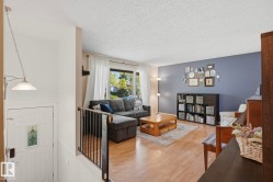 Spacious living area featuring wood-finish flooring, a large window, and a built-in bookshelf - 
