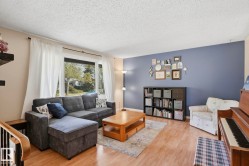 Bright living area featuring wood-finish flooring, a large window, and a built-in shelving unit - 