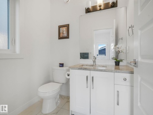White vanity with a granite-style countertop, undermount sink, and polished chrome faucet - 3807 Weidle Crescent Sw, Edmonton, AB 