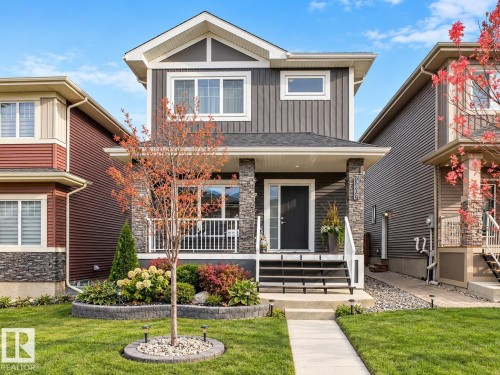 Gabled roofline, stone facade accents, covered front porch, concrete walkway, and manicured lawn - 3807 Weidle Crescent Sw, Edmonton, AB 
