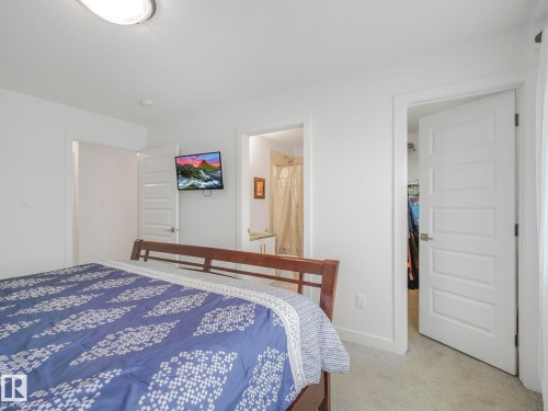 White interior doors, wall-mounted television, and flush-mount ceiling light fixture - 3807 Weidle Crescent Sw, Edmonton, AB 