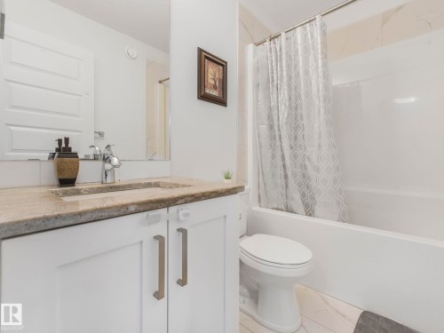 White vanity with a stone-finish countertop, integrated rectangular sink, and chrome faucet - 3807 Weidle Crescent Sw, Edmonton, AB 