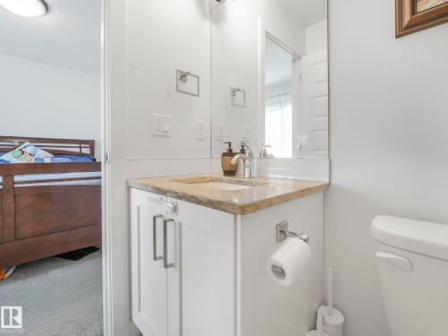 Vanity with a polished stone countertop, integrated sink, chrome faucet, and white cabinetry with modern pulls - 3807 Weidle Crescent Sw, Edmonton, AB 