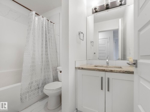 White vanity with a neutral-toned countertop and an integrated sink - 3807 Weidle Crescent Sw, Edmonton, AB 
