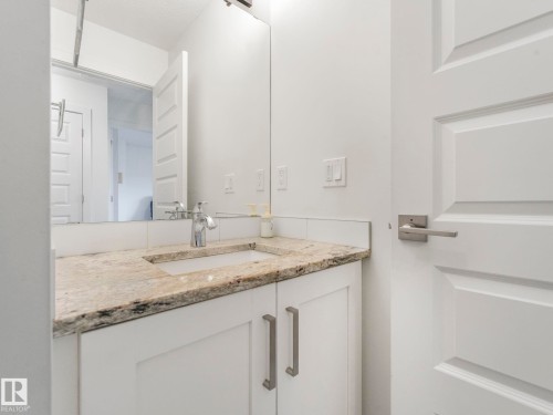 White vanity with a polished chrome faucet, under-mount sink, and light-toned countertop - 3807 Weidle Crescent Sw, Edmonton, AB 