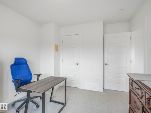 Neutral white walls, light gray carpet, and two paneled interior doors with modern hardware - 3807 Weidle Crescent Sw, Edmonton, AB 