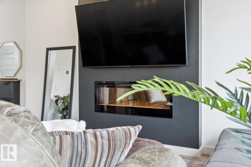 Built-in linear fireplace with a dark surround, complementing the wall-mounted television - 22434 99A Avenue Nw, Edmonton, AB 