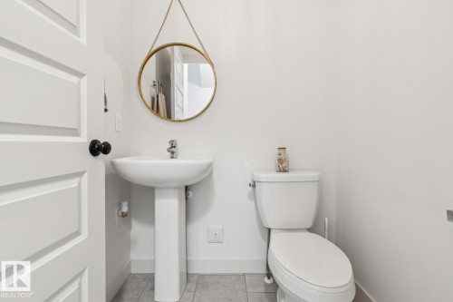 White paneled door with a black doorknob, pedestal sink, and a white toilet - 22434 99A Avenue Nw, Edmonton, AB 