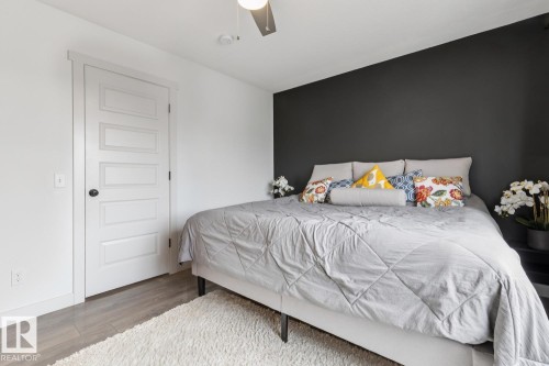 Wood-finish flooring, white paneled door with dark hardware, ceiling fan with integrated lighting, accent wall, and white painted walls - 22434 99A Avenue Nw, Edmonton, AB 