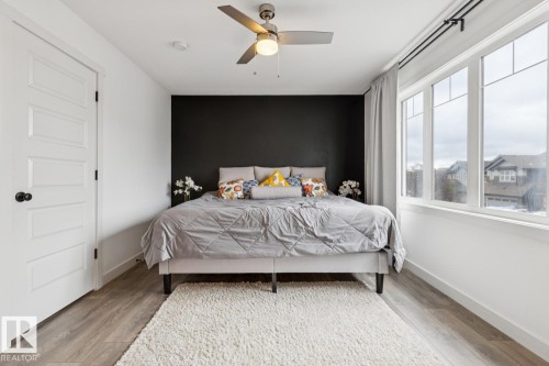 Wood-finish flooring, a contemporary ceiling fan, and large windows with white trim - 22434 99A Avenue Nw, Edmonton, AB 