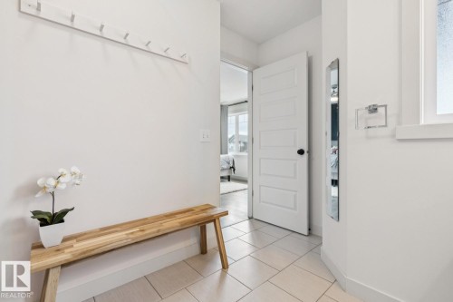 Light-toned tile flooring, white interior paneled door, wall-mounted coat rack, and recessed window - 22434 99A Avenue Nw, Edmonton, AB 