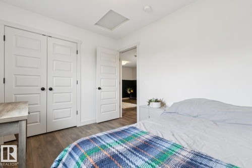 White walls, wood-finish flooring, two panel-style doors, and a ceiling light fixture - 22434 99A Avenue Nw, Edmonton, AB 