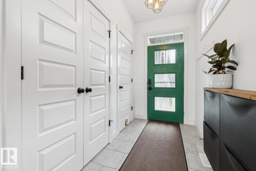 Green entry door with three glass inserts, flanked by white paneled doors with matte black hardware - 22434 99A Avenue Nw, Edmonton, AB 