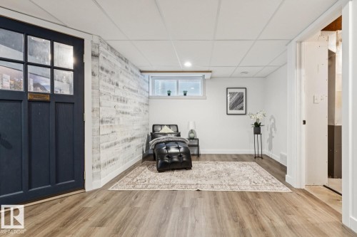 Wood-finish flooring, drop ceiling with recessed lighting, whitewashed plank accent wall, and a window with blinds - 22434 99A Avenue Nw, Edmonton, AB 