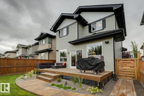 Rear exterior featuring a wood deck, sliding glass door, and a wood privacy fence - 22434 99A Avenue Nw, Edmonton, AB 