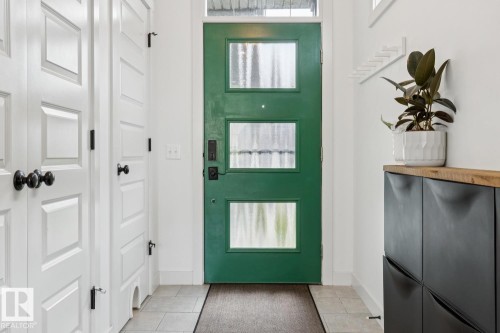 Green entry door with multiple glass panels, white paneled doors, and light tile flooring - 22434 99A Avenue Nw, Edmonton, AB 