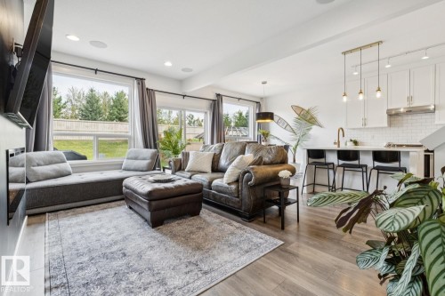Open-concept living area with wood-finish flooring, recessed lighting, and large windows - 22434 99A Avenue Nw, Edmonton, AB 