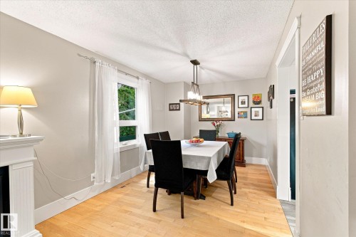 Light-filled interior space featuring wood-finish flooring, a contemporary chandelier, and a built-in mantelpiece - 3 Akins Drive, St. Albert, AB 