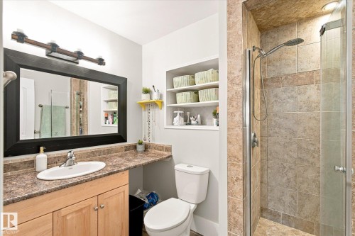 Built-in shower with glass enclosure, wood-finish vanity with counter space, framed mirror, and recessed wall shelving - 3 Akins Drive, St. Albert, AB 