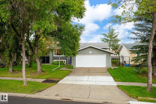 Attached front-facing garage with a white door, light gray siding, and a gabled roof - 3 Akins Drive, St. Albert, AB 