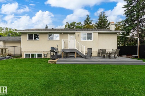 Expansive lawn area with a composite deck, white railing, and stucco exterior - 3 Akins Drive, St. Albert, AB 
