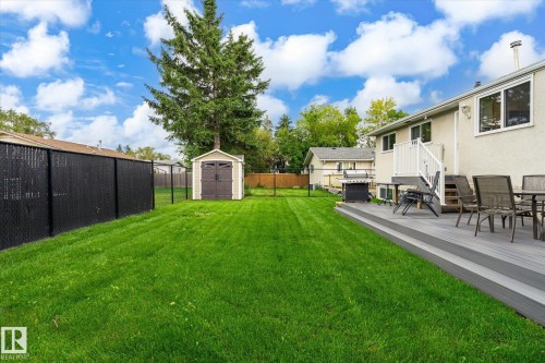 Expansive green lawn with a storage shed, a two-tier composite deck, and privacy fencing - 3 Akins Drive, St. Albert, AB 