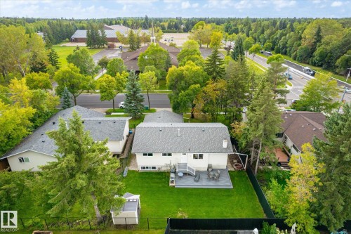 Expansive backyard with a manicured lawn, a large deck, and mature trees - 3 Akins Drive, St. Albert, AB 