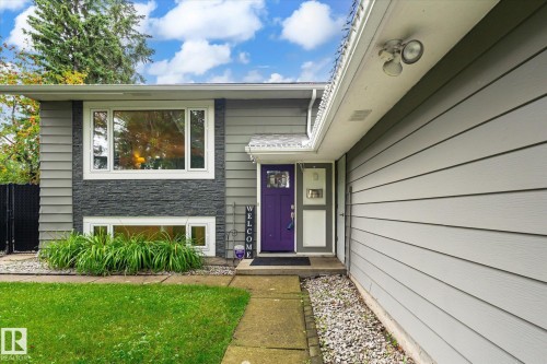 Gray siding exterior with a prominent purple entry door, stone-finish accent paneling, and white-framed windows - 3 Akins Drive, St. Albert, AB 